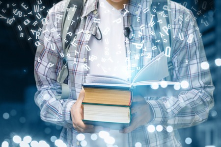 Student showing textbooks of which fly letters on a blurred background.