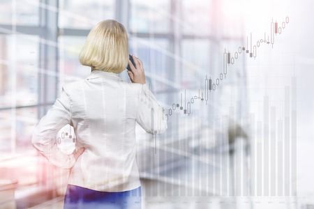 Businesswoman talking on the phone on the background of financial growth.