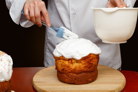 A female cooker is covering the rum cake with the foam cream. The concept is preparation for the holiday.の写真素材