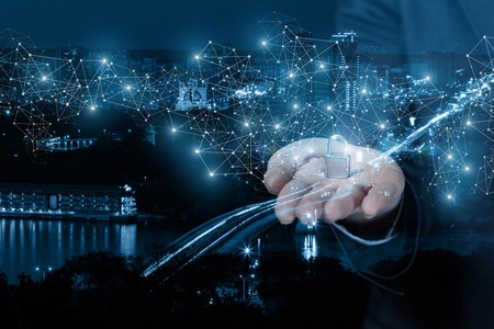 A businesswoman is holding a padlock on her arm surrounded by digital wireless connections at the...