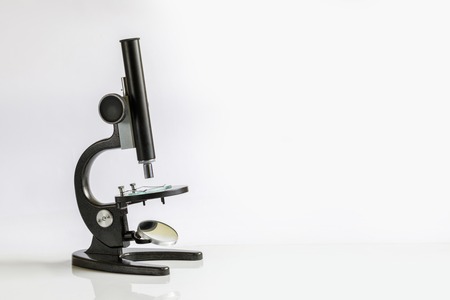 A microscope with some substance on its working surface is standing on the flat white area. The concept is the researching laboratorian equipment.の写真素材