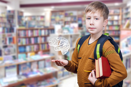 A pupil with a schoolbag behind his back is standing inside the school library full of different...