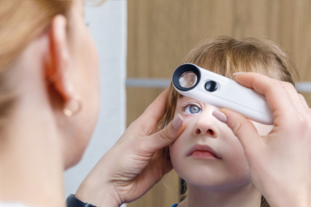 A closeup of female ophthalmologist checking eye of small child or performing the post treatment...
