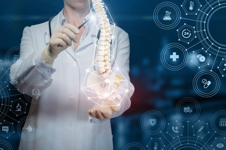 Doctor shows a human spine on blue background.の写真素材