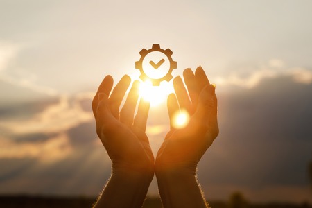 Hands support the symbol of the quality standard certification against the sky.の写真素材