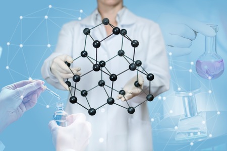 The laboratory worker shows a crystal lattice on a blue background.の写真素材
