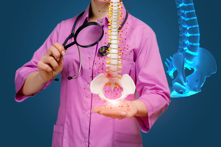 Doctor with a magnifying glass examines a disease of the spine on a blue background.の写真素材