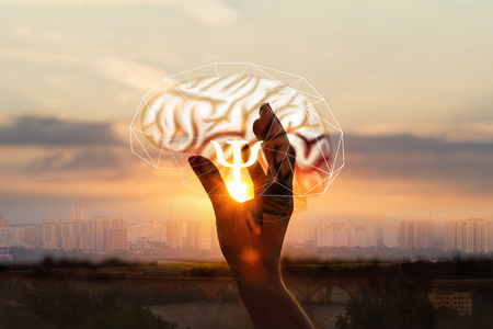 The hand shows the symbol of the psychologists on the background of the human brain.