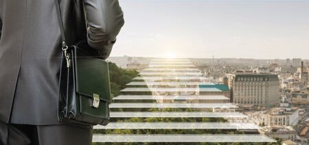 Businessman in front of corporate ladder in the background of the city.の写真素材