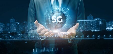 The 5G network connection concept .A man shows 5G on the background of the city.の写真素材