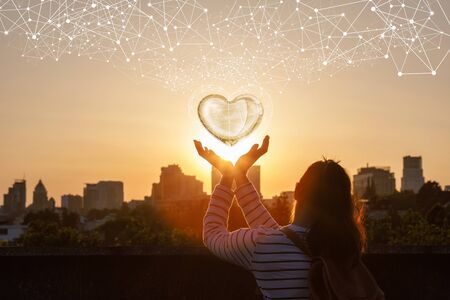 The woman maintains the heart on the background of sunset.の写真素材
