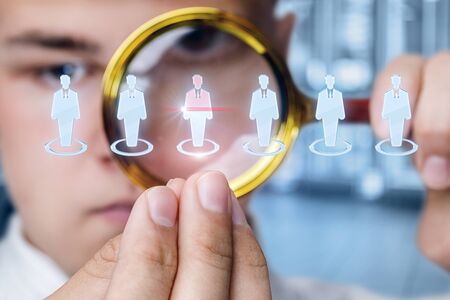 The concept of the choice of the employee . Businessman studies candidates with a magnifying glass.の写真素材
