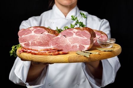 Cook shows sliced ham on a dark background.