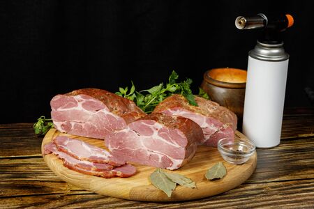 Cooked ham on a wooden table against a dark background.の写真素材