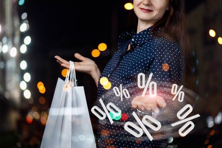The woman shows the percentage discount on blurred background.の写真素材