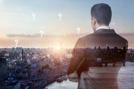 The concept answers to the questions. Businessman thinking over the issues raised by the panorama of the city.の写真素材