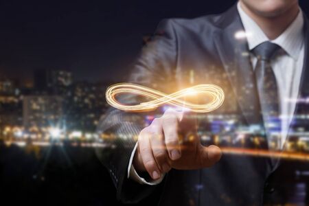The businessman clicks the infinity sign on blurred background.の写真素材
