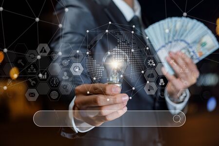 Concept search for ideas to earn money. Businessman showing light bulb and banknotes of dollars on a background search.の写真素材
