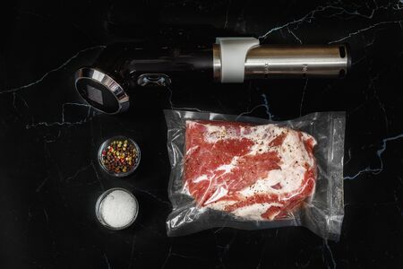 Cook sous vide immersion circulator cooker and the meat Packed a black background.の写真素材