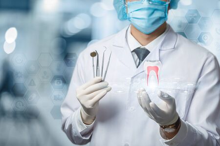 The concept of the provision of dental treatment. Doctor shows a tooth on blurred background.