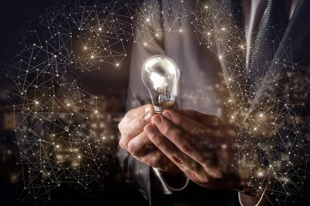The concept of global ideas.Businessman holds a burning light bulb in the global network.