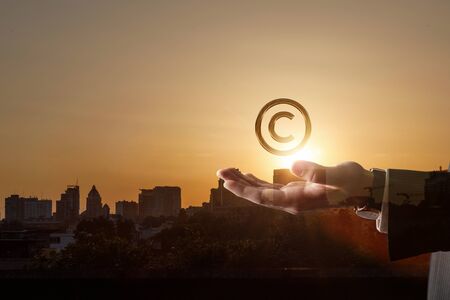 A lawyer shows a copyright sign against the backdrop of an urban sunset.の写真素材