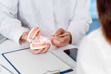 The doctor explains to the patient how to protect teeth from tooth decay.