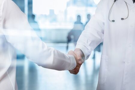 Doctor shakes hands with a businesswoman on blurred background.の写真素材