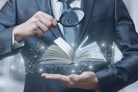 The concept of information search in textbooks.A man is watching a study guide through a magnifier.の写真素材
