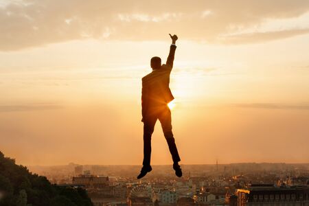 The concept of business success.Businessman jumping for joy on the background of the cityscape.の写真素材