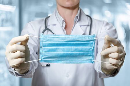 Doctor show a protective mask on a blurred background.の写真素材