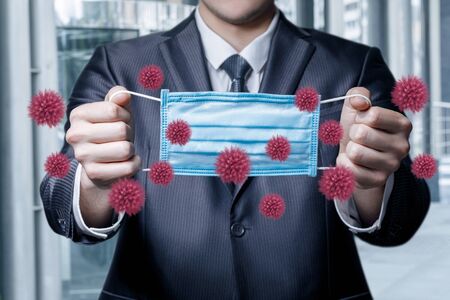 The concept of a protective mask against the virus. Businessman holds a mask protective against viruses.の写真素材