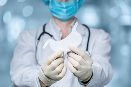 The concept of diagnosis and treatment of the patient stomach. The doctor holds the stomach on a blurred background.の写真素材