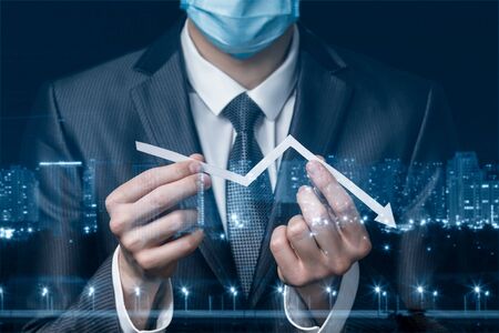 The concept of financial crisis during an epidemic. Businessman in protective mask showing Graph of...