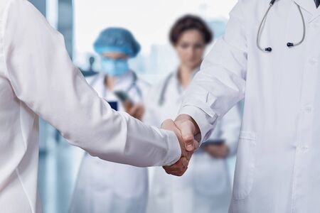 Doctors shake hands on a blurred background.の写真素材