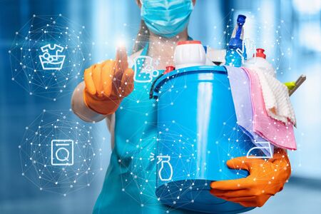 A cleaning lady clicks on the cleaning service icon on a blurred background.の写真素材