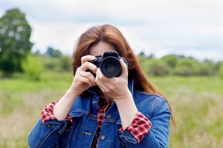 Woman photographer takes pictures with a camera on a blurred background.の写真素材