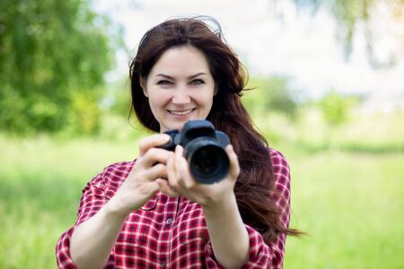 Woman smiles with a camera in her hands on a blurred background.の写真素材
