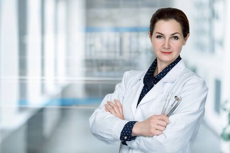 Woman dentist doctor with tools in hands on a blurred background.の写真素材