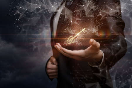 Key to success concept. Businessman shows a key on a blurred background.の写真素材