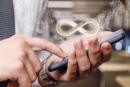 An infinity sign appears from the phone on a blurred background.の写真素材