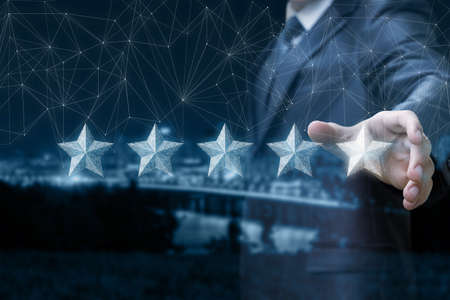 The concept of rating on the Internet.The businessman shows a hologram of stars on the background of...