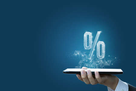 The concept of discounts on the Internet. The hand with the tablet shows the hologram percent.の写真素材