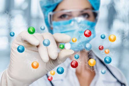 Doctor shows a pill containing a large amount of vitamins on a blurred background.