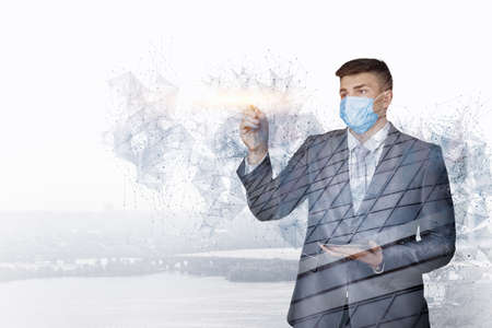 A businessman in a protective mask works the network against the background of the city.の写真素材