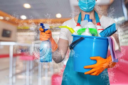 Cleaning services concept.A cleaning lady with a bucket and cleaning products stands on a blurred background.の写真素材