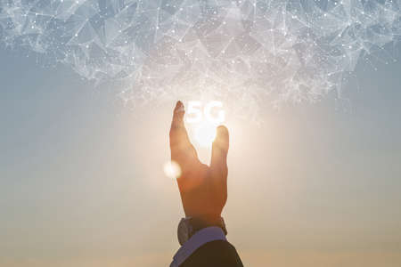 Hand of businessman shows 5g on background of sunny sunset.の写真素材