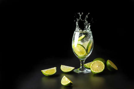 Splash of water in a glass with lime and ice on a black background.の写真素材