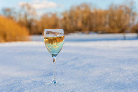 A glass of wine stands in the snow on a blurred background in spring.の写真素材