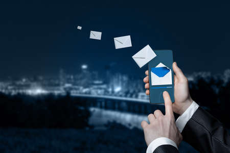 Email marketing business concept. Businessman sends emails by phone.の写真素材